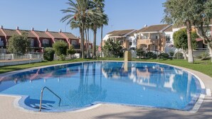 A swimming pool surrounded by residential buildings with a clear sky. - Marina Place in Chiclana de la Frontera (Chiclana de la Frontera)