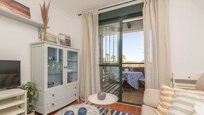 A living room with a sofa, a TV, a cabinet, and a small table with decorative items. - Marina Place in Chiclana de la Frontera (Chiclana de la Frontera)