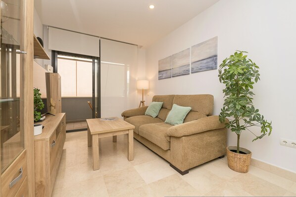 A modern living room with a sofa, a wooden coffee table, a potted plant, and a painting on the wall. - La Yerbabuena in Barbate (Barbate)