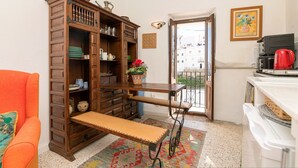 A compact kitchen with a wooden cabinet, a bench, a coffee machine, and a view of the outside. - La Azucena in Vejer de la Frontera (Vejer de la Frontera)