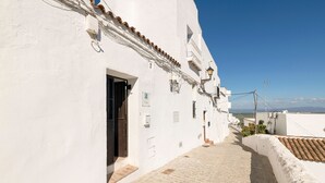 A narrow cobblestone street flanked by white buildings with tiled roofs and a clear blue sky. - La Azucena in Vejer de la Frontera (Vejer de la Frontera)