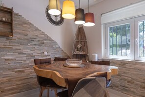 Un comedor con una mesa de madera, sillas e iluminación colgante.