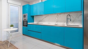 Une cuisine moderne avec des meubles bleus, un pare-feu en marbre blanc et des appareils électroménagers en acier inoxydable.