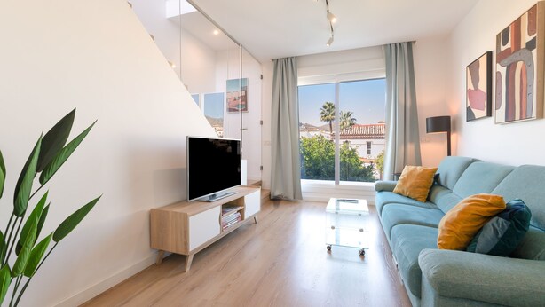 Un salon moderne avec un téléviseur à écran plat, un canapé et une table basse en verre.