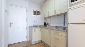 Una cocina compacta con armarios de madera clara, encimera de granito y microondas integrado.