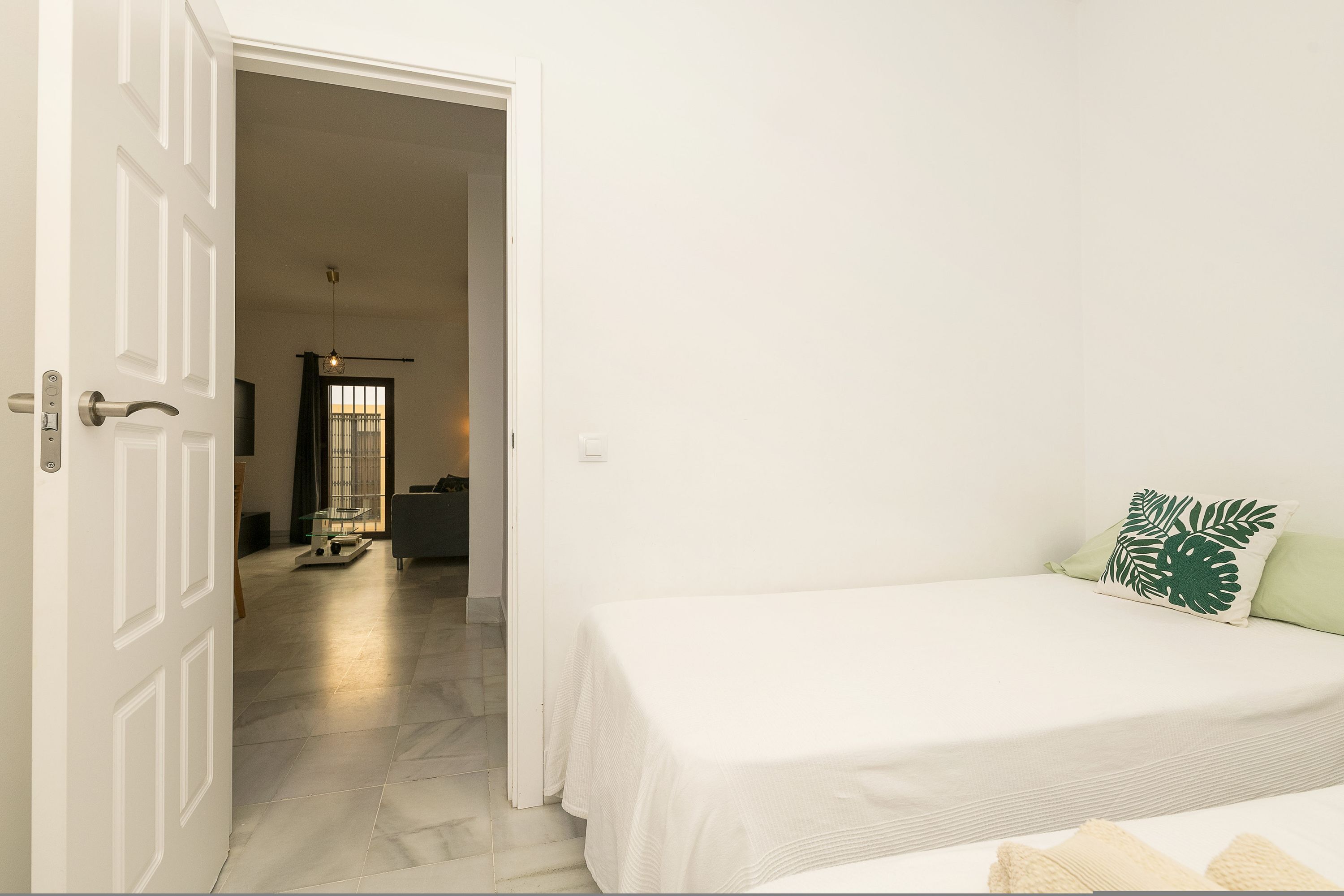 Un dormitorio con cama, una puerta y un pasillo que lleva a otra habitación.
