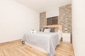 A bedroom with a bed, nightstand, and a window with a view of the outside. - Casa Roja in La Ribera de la Oliva (Vejer de la Frontera)
