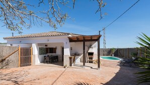 Una casa con patio, zona de barbacoa y piscina.