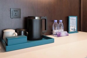 A hotel room's side table with a coffee maker, two water bottles, a mug, and a framed menu. - Bonny International Hotel (Lengshuijiang)