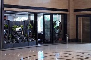 Un vestíbulo con entrada de vidrio, un mostrador de recepción y una decoración floral.