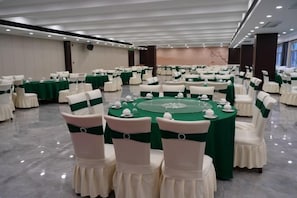 A banquet hall with round tables, chairs, and green tablecloths. - Bonny International Hotel (Lengshuijiang)