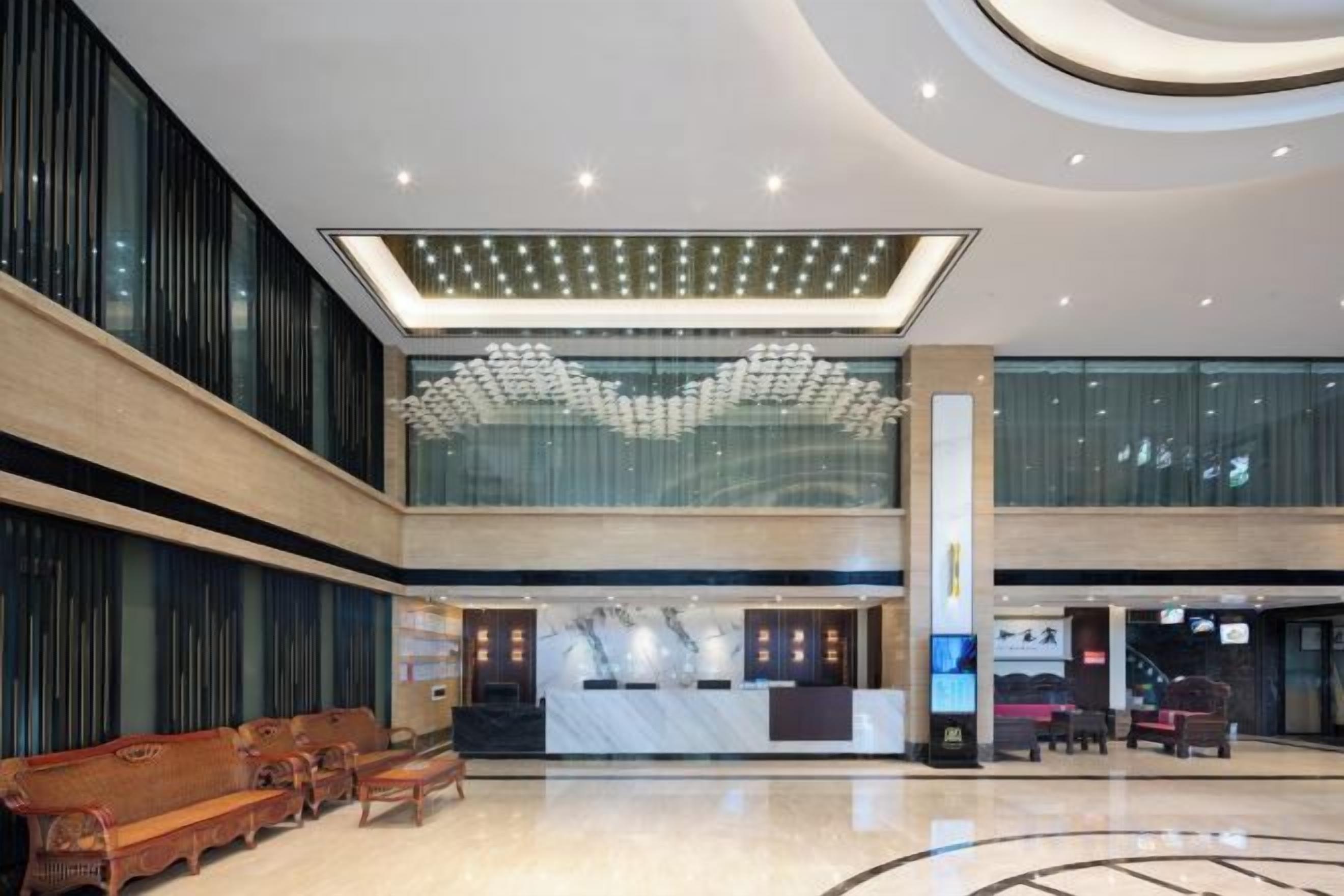 Eine großzügige Lobby mit einer Rezeption, einer Sitzecke und einer großen Glaswand.