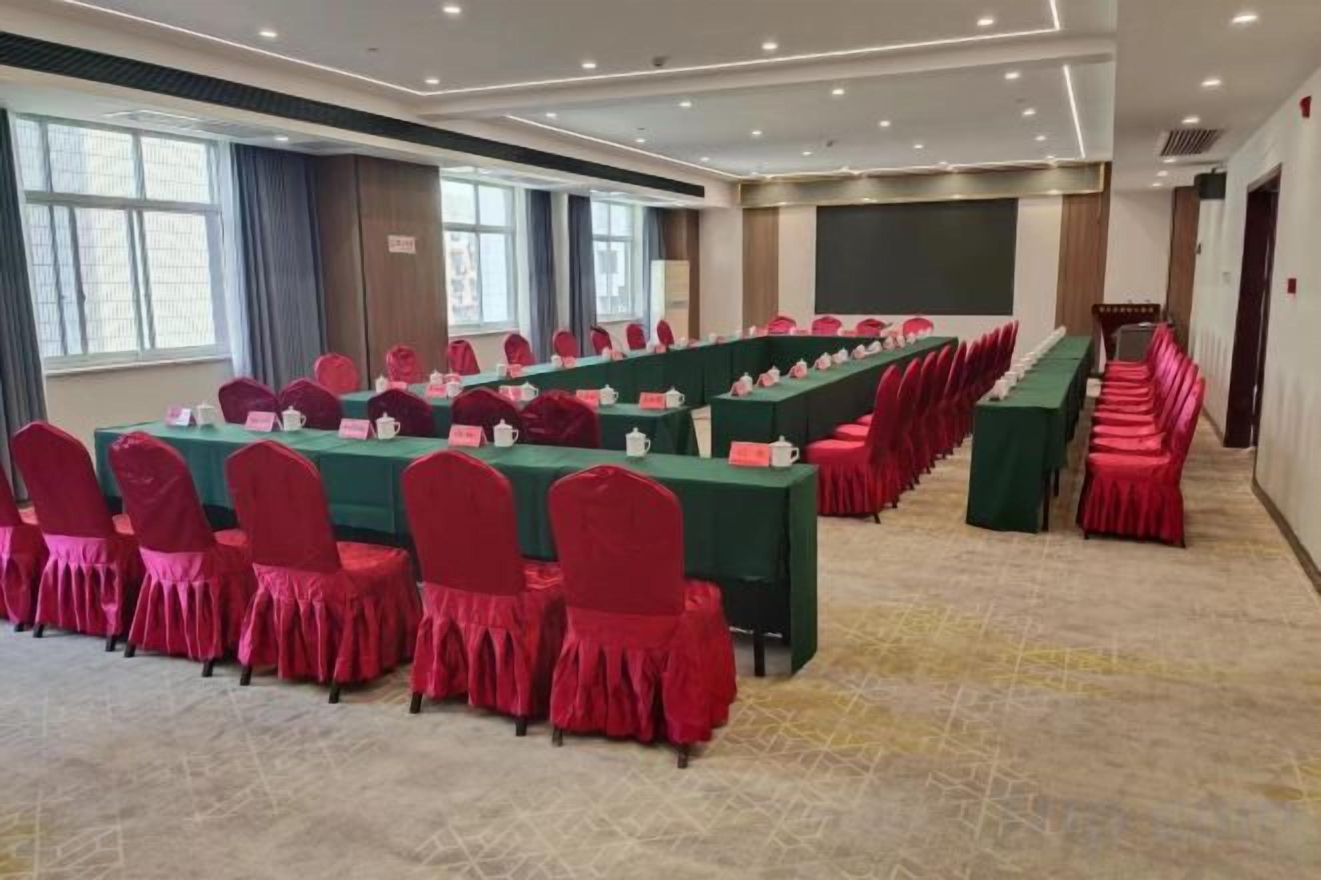 A conference room with multiple tables and chairs, a projector screen, and a stage area.