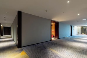 A modern hotel corridor with a patterned carpet, a dark wall, and a door leading to a room. - Bonny International Hotel (Lengshuijiang)