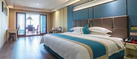 Habitación de hotel con una cama grande, un escritorio y una silla. Se aprecia vista al exterior a través de amplios ventanales.
