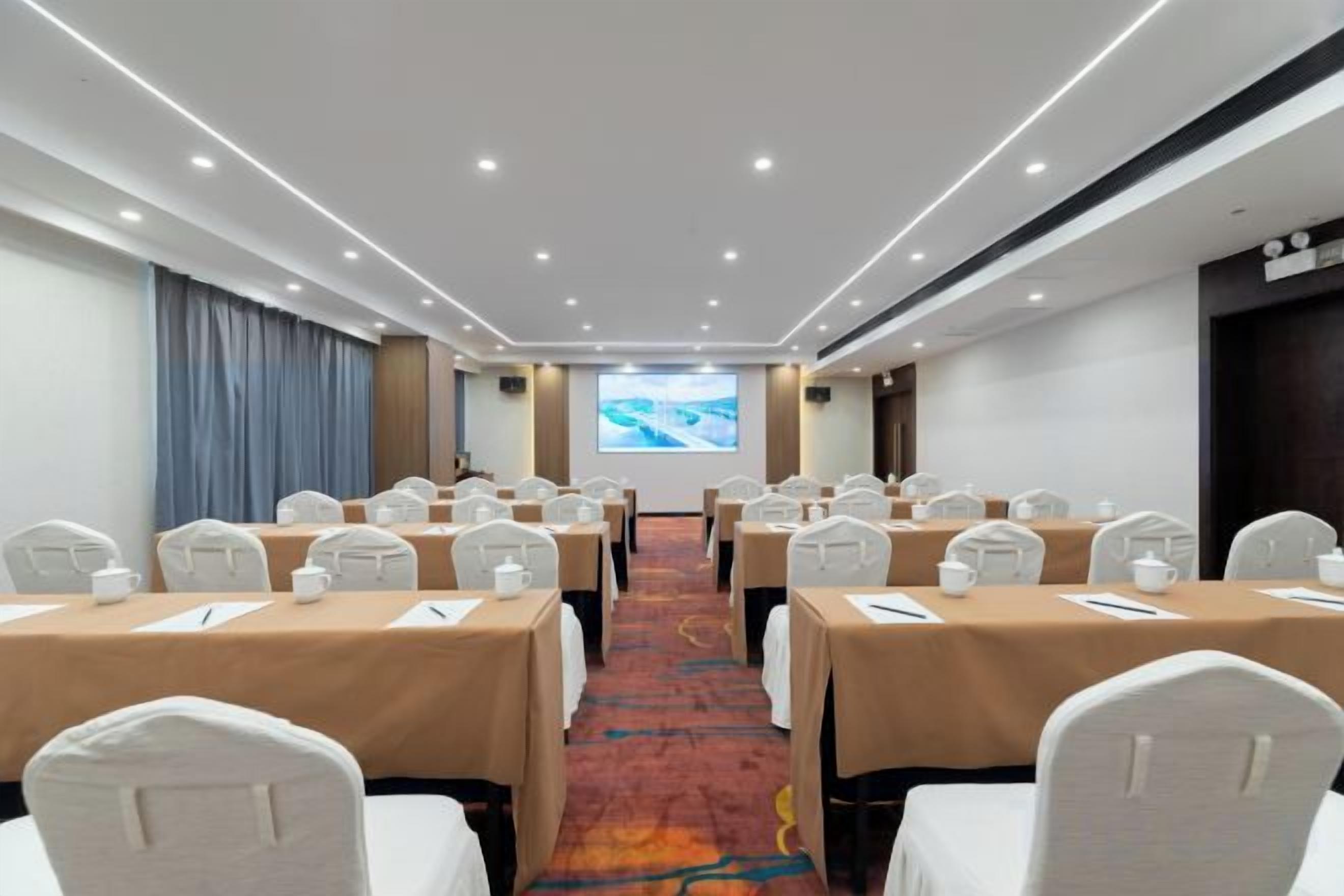 A conference room with tables, chairs, and a presentation screen.