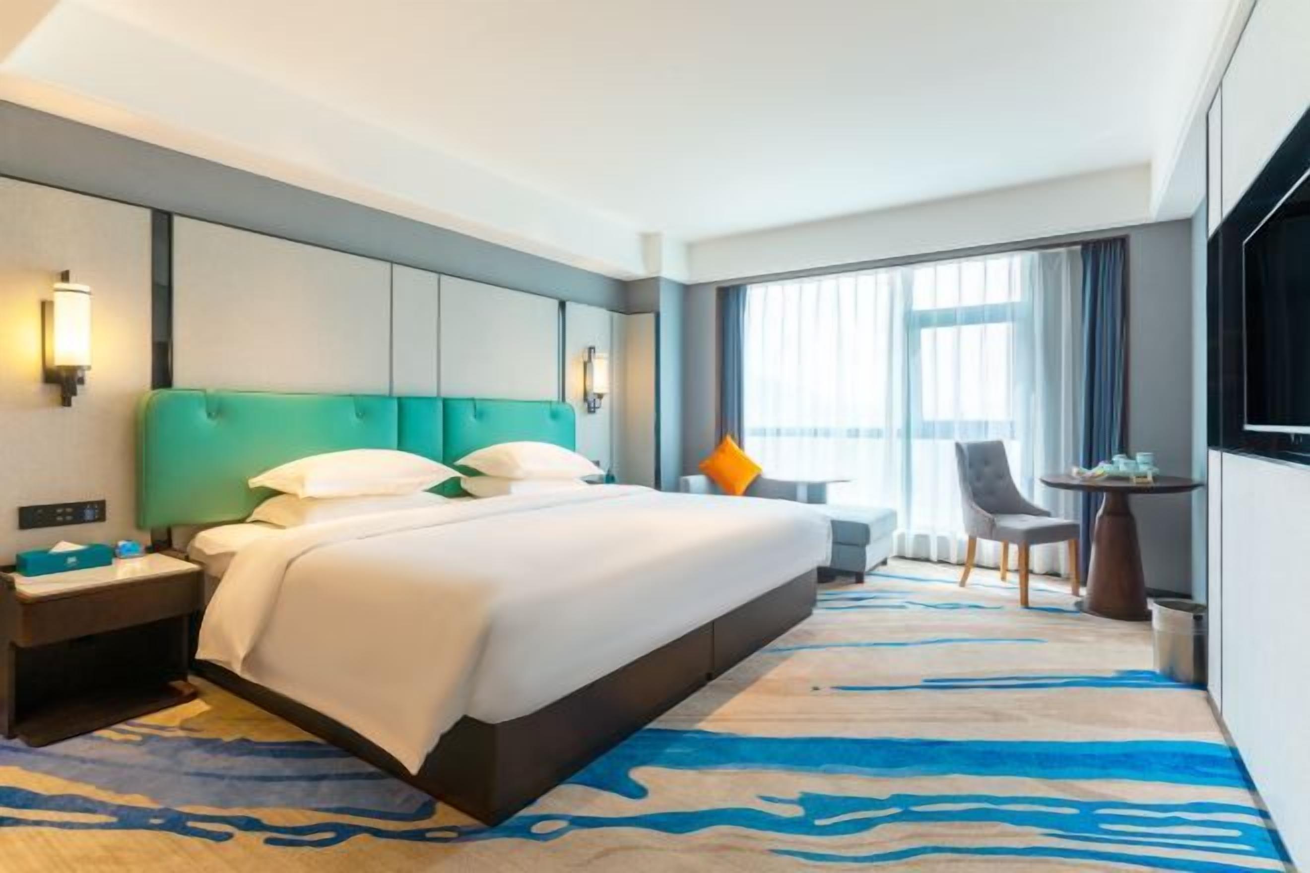A hotel room with a large bed, a desk, and a chair.