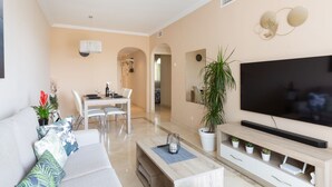 Un soggiorno moderno con divano, TV e zona pranzo.