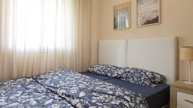 A bedroom with a bed, a nightstand, a lamp, and two wall art pieces.