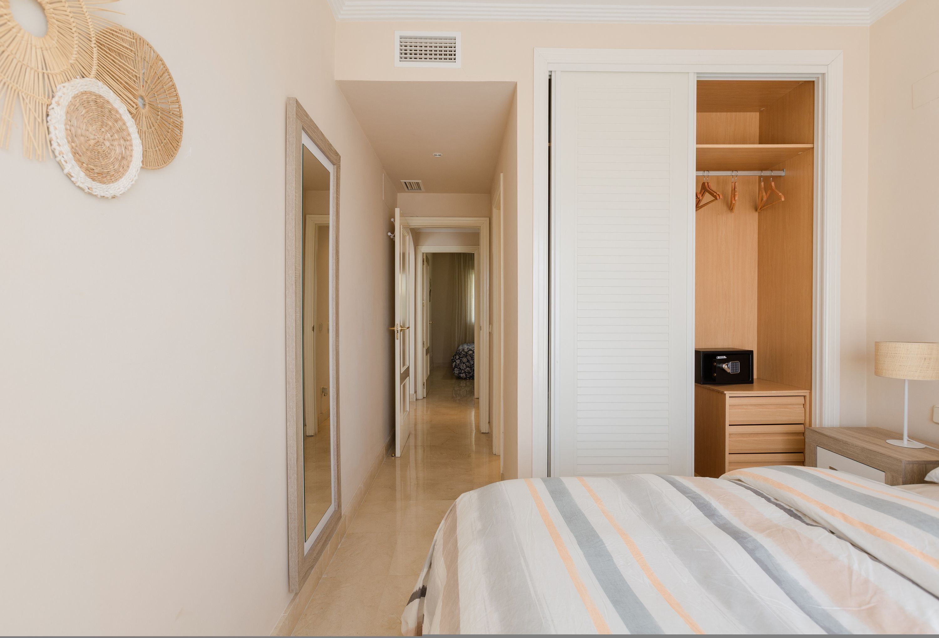 A hotel room with a bed, a wardrobe, a bedside table, and a lamp.