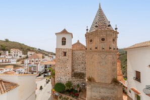 Un edificio histórico con un campanario y una torre de reloj, rodeado de edificios blancos con tejados de tejas rojas.