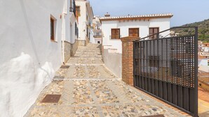 Un carrer estret amb un camí empedrat que condueix a una entrada amb porta.