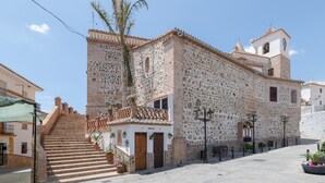 Edifici de pedra històric amb una torre campanar, una escala que condueix a l'entrada i un pati empedrat.