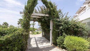 Un vialetto che si snoda in un rigoglioso giardino, con un pergolato ricoperto di vegetazione.