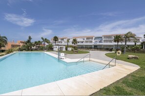 A swimming pool with a clear blue water, surrounded by a concrete deck and a grassy area. - Mirador Del Estrecho (Tarifa)