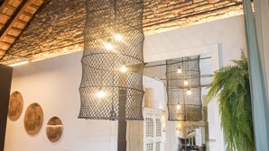 Ein modernes Interieur mit hängenden Drahtleuchten, einem großen Topf-Farn und einer Ziegeldecke.