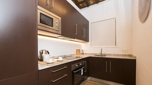 Eine moderne Küche mit dunklen Schränken, einer eingebauten Mikrowelle, einem Edelstahlbackofen und einer Marmorarbeitsplatte.
