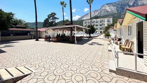 Cortile di un hotel con posti a sedere all'aperto, piscina e vista sulle montagne.