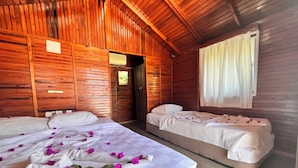 Una baita in legno con due letti, uno con copriletto bianco e l'altro color beige.