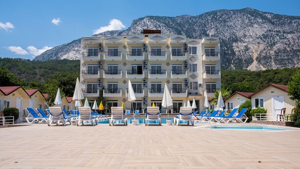 Un hotel con diversi balconi, una piscina e montagne sullo sfondo.