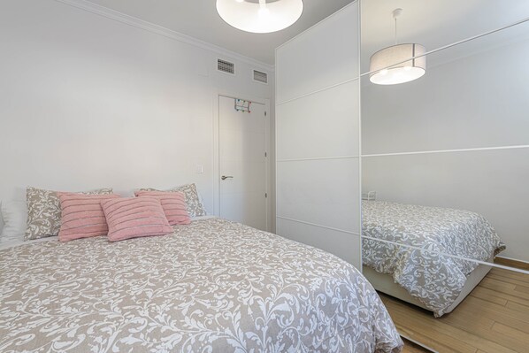 A bedroom with a bed, a large mirror, and a door.