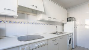 Une cuisine avec des meubles blancs, un four à micro-ondes, un lave-linge et un évier.