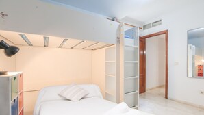Une chambre à coucher comprenant un lit, une armoire, un miroir et une porte donnant sur une autre pièce.