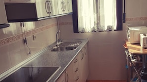 Una cuina amb un rentaplatets d'acer inoxidable, un forn integrat i una torradora al taulell.