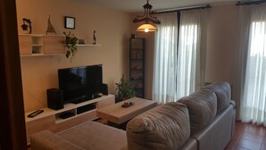 Un saló amb televisió de pantalla plana, taula de centre de fusta, sofà i una planta en test.