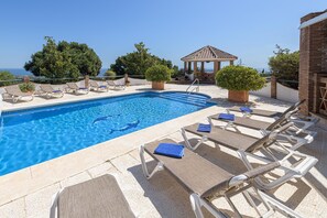 Un área de piscina con sillones de descanso y un pabellón.