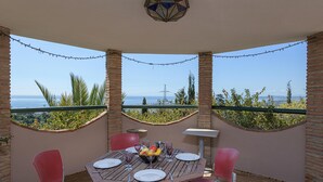A patio with a table set for four, surrounded by brick walls and red chairs, overlooking a scenic view. - Villa Lina in Estepona (Estepona)