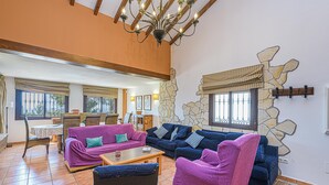 A spacious living area with multiple sofas and chairs, a wooden ceiling, and a stone accent wall. - Villa Lina in Estepona (Estepona)