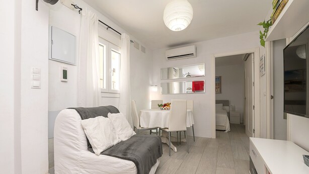 A modern, well-lit living room with a sofa, a dining table, and a kitchen area. - Retiro Al Amanecer in Chiclana de la Frontera (Chiclana de la Frontera)