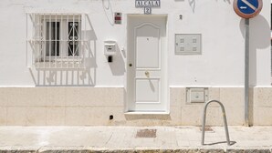 A white building with a door labeled "ALCALA 2", a window with metal bars, and a no parking sign. - Retiro Al Amanecer in Chiclana de la Frontera (Chiclana de la Frontera)