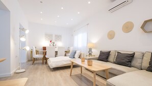 Una sala moderna con un sofá, una mesa de madera y un comedor con sillas.