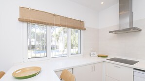 Una cocina moderna con un ventanal grande, armarios blancos y un lavavajillas integrado.