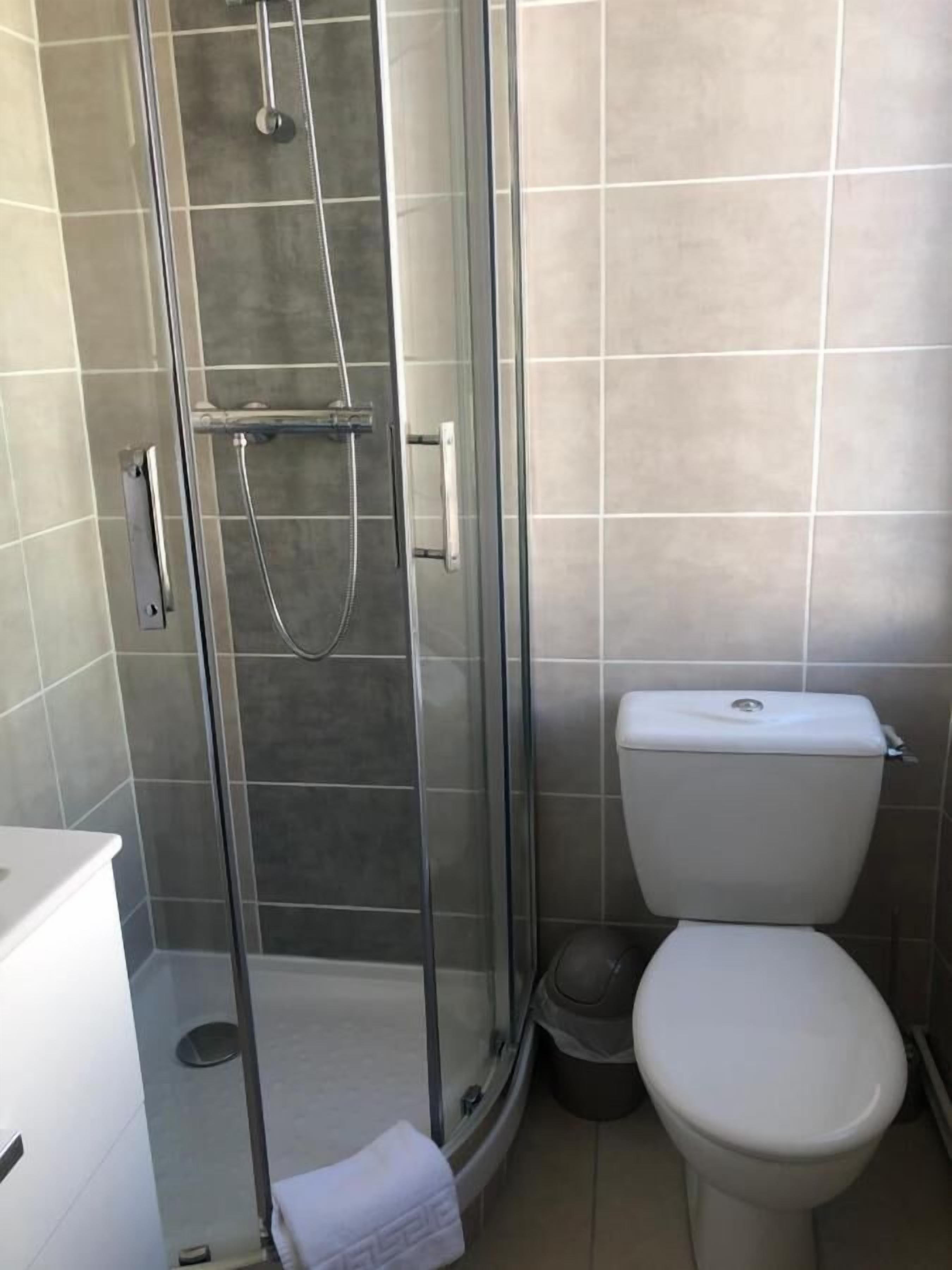 Un baño con ducha de vidrio, inodoro y lavamanos.