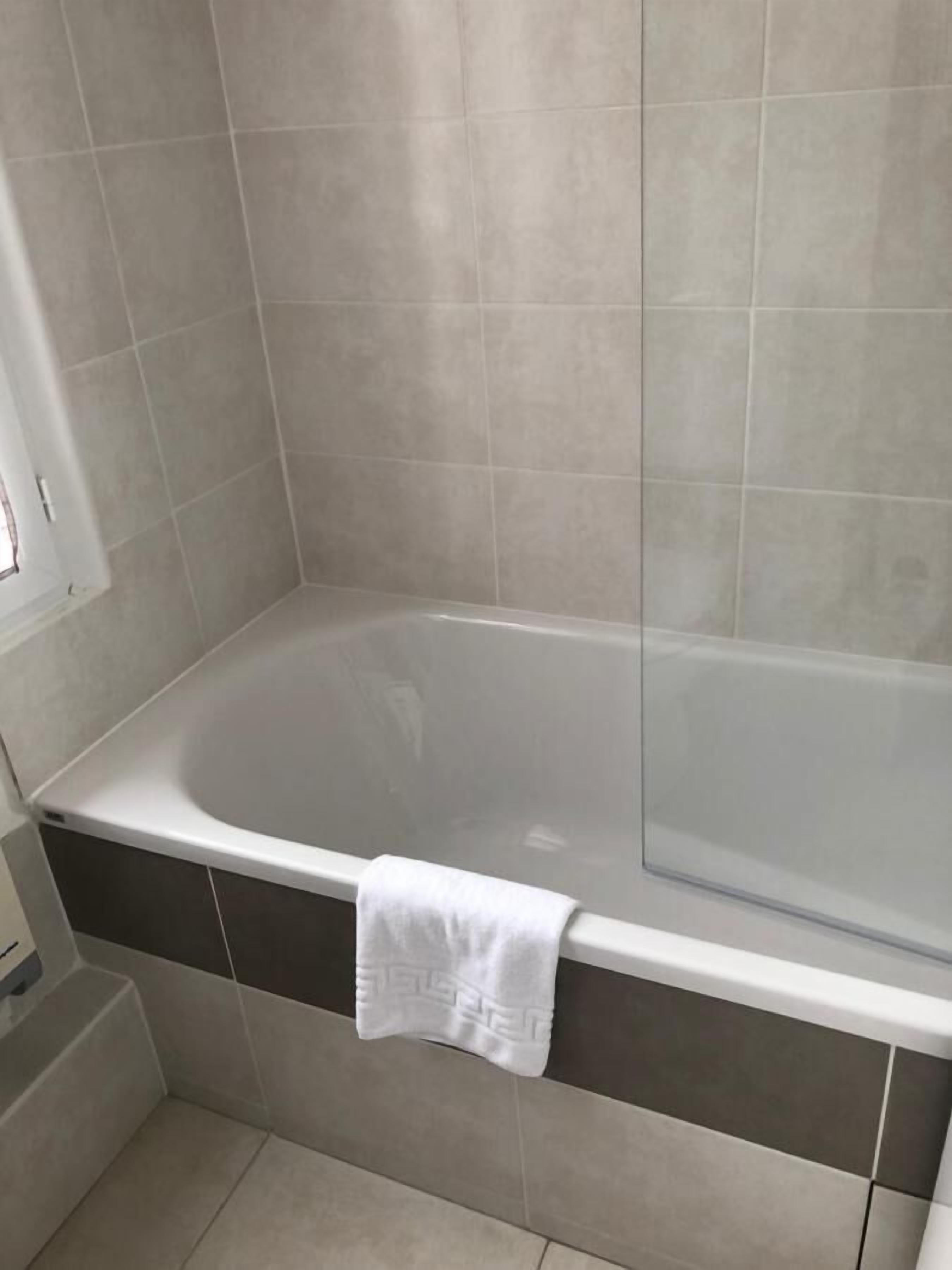 Une salle de bain moderne avec une baignoire sur pieds, une serviette suspendue sur le côté et une fenêtre laissant entrer la lumière naturelle.