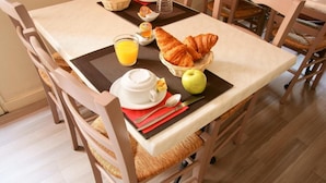 A breakfast setup with croissants, an apple, a glass of orange juice, and a cup of coffee on a table. - Le Central Hôtel (Niort)