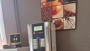 A coffee machine with a digital interface, a microwave, and a refrigerator on a kitchen counter. - Le Central Hôtel (Niort)